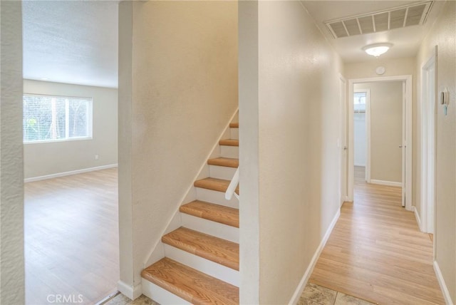 stairs featuring wood finished floors, visible vents, and baseboards