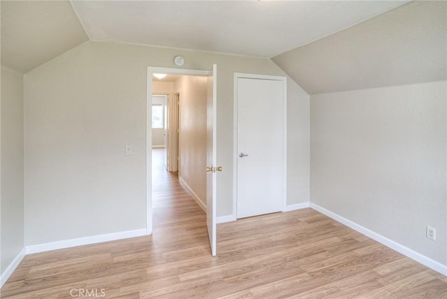 bonus room featuring light wood-type flooring, lofted ceiling, and baseboards