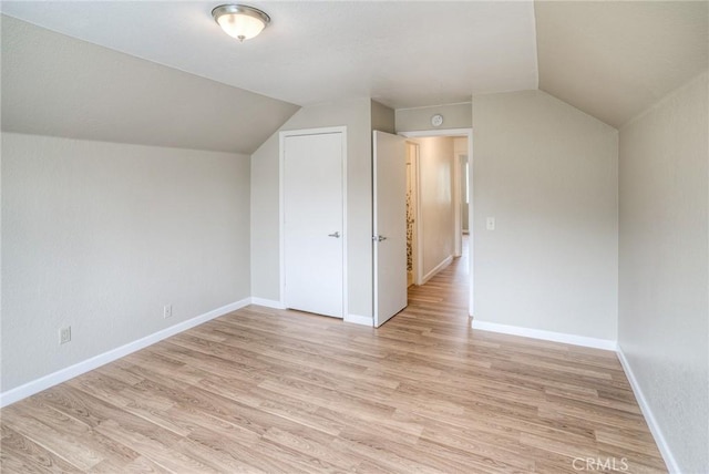 additional living space with lofted ceiling, light wood-style flooring, and baseboards