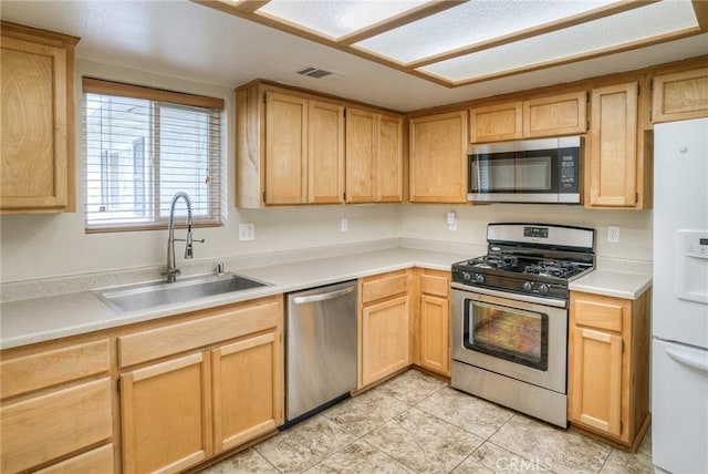 kitchen with appliances with stainless steel finishes, light brown cabinets, and a sink