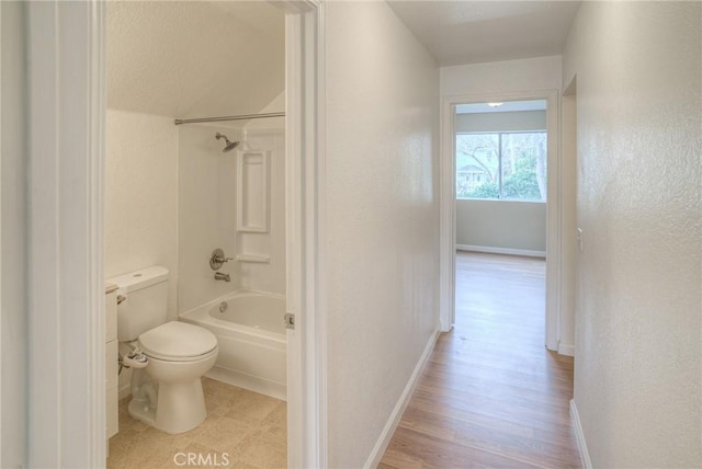 bathroom featuring shower / washtub combination, wood finished floors, toilet, and baseboards