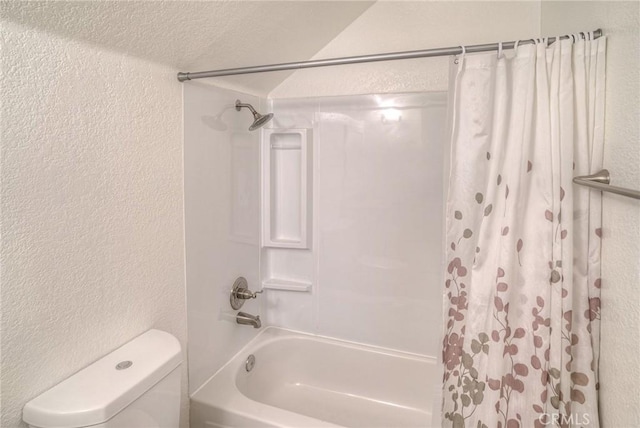 full bathroom with a textured wall, toilet, and shower / bath combo with shower curtain