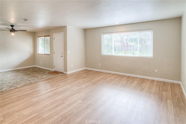 empty room featuring wood finished floors, a ceiling fan, and baseboards