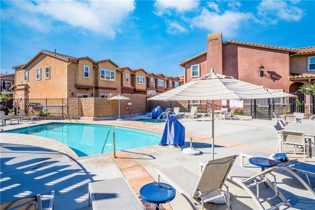 community pool featuring a residential view, a patio area, and fence