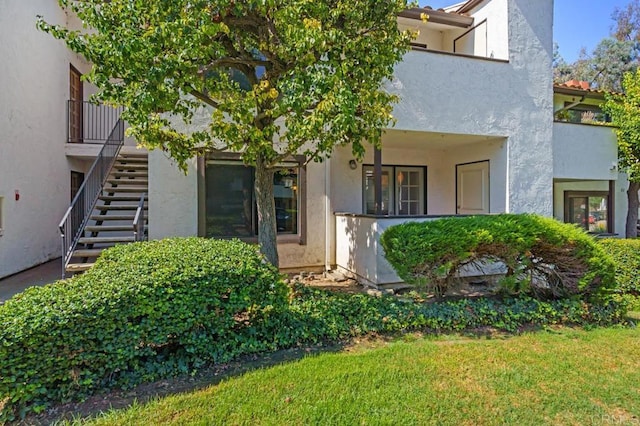 entrance to property featuring a yard and stucco siding