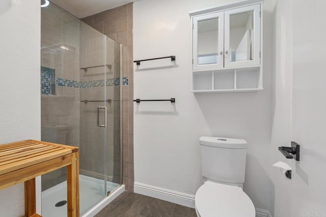 bathroom featuring toilet, a stall shower, baseboards, and wood finished floors