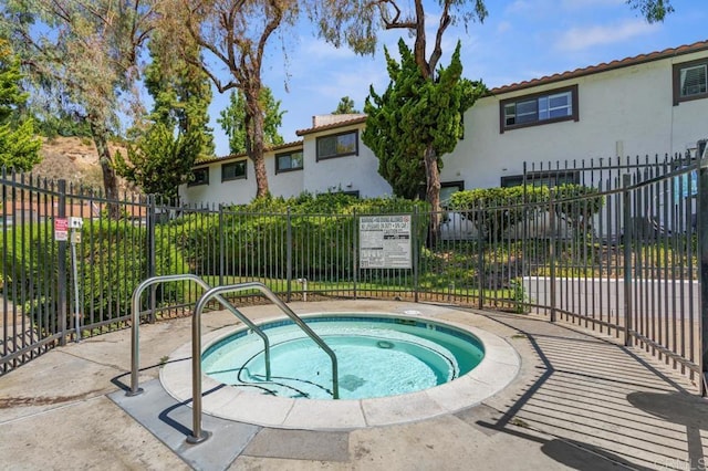 view of swimming pool with fence and a hot tub