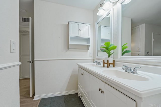 full bath with double vanity, a sink, visible vents, and baseboards