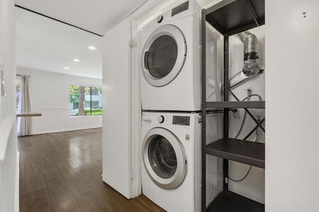 laundry area with recessed lighting, stacked washer and dryer, laundry area, dark wood-style flooring, and baseboards