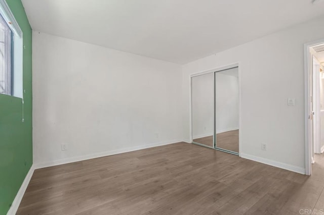 unfurnished bedroom with a closet, baseboards, and wood finished floors