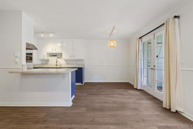 kitchen featuring a peninsula, a sink, white cabinetry, hanging light fixtures, and french doors