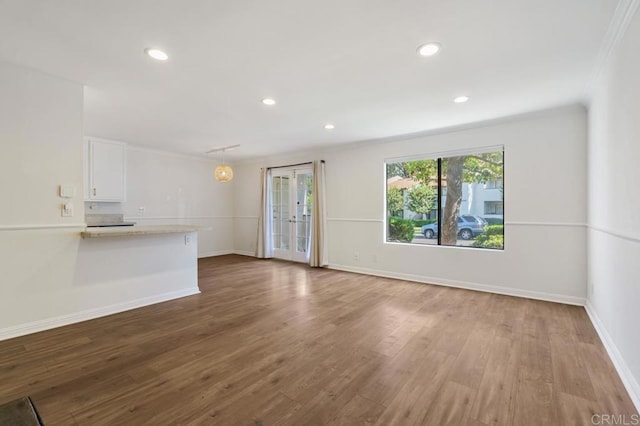 unfurnished living room with recessed lighting, french doors, baseboards, and wood finished floors