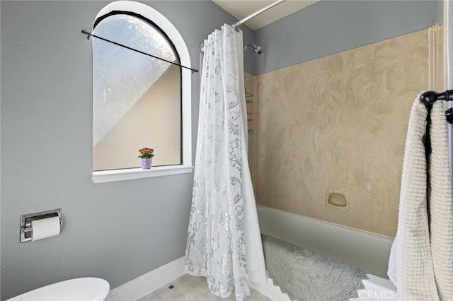 bathroom featuring baseboards, shower / bathtub combination with curtain, and toilet