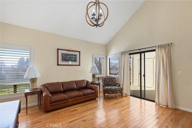 living room featuring high vaulted ceiling, light wood-style flooring, baseboards, and a notable chandelier