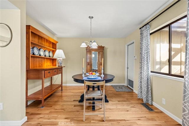 dining room with baseboards, an inviting chandelier, visible vents, and light wood-style floors