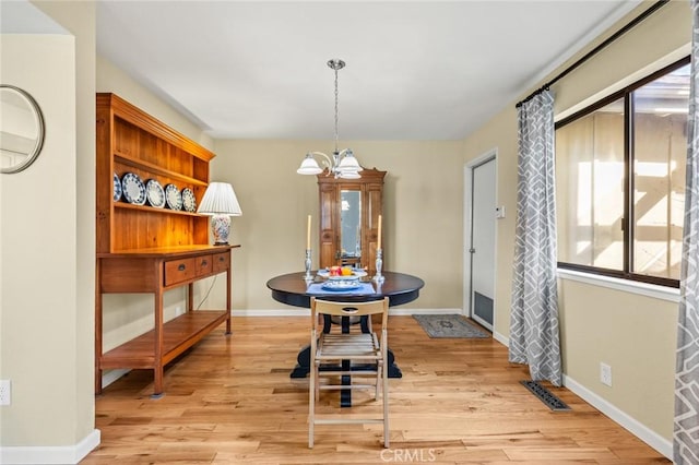 dining room featuring visible vents, baseboards, a chandelier, and light wood-type flooring