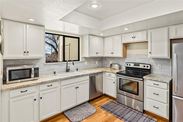 kitchen with a sink, white cabinets, and stainless steel appliances