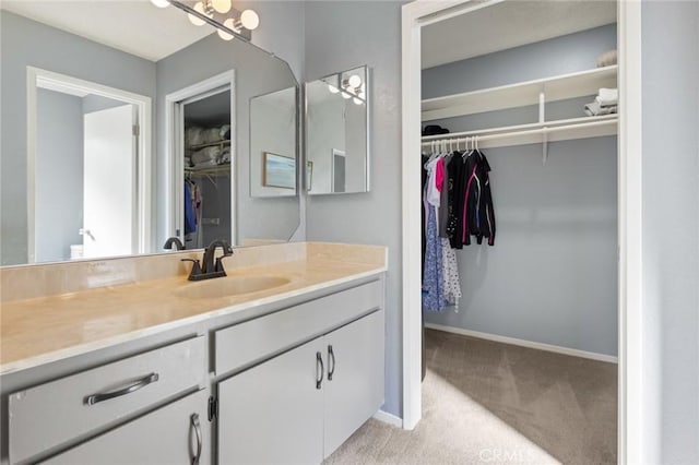bathroom with vanity, baseboards, and a walk in closet
