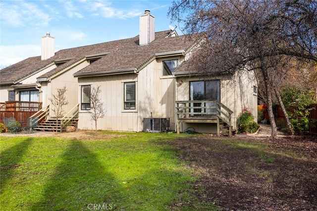 rear view of property with a deck, central AC, a yard, roof with shingles, and a chimney