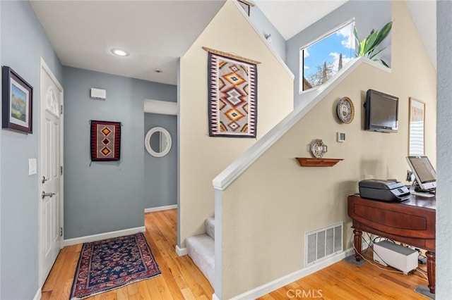 stairway with baseboards, visible vents, and wood finished floors