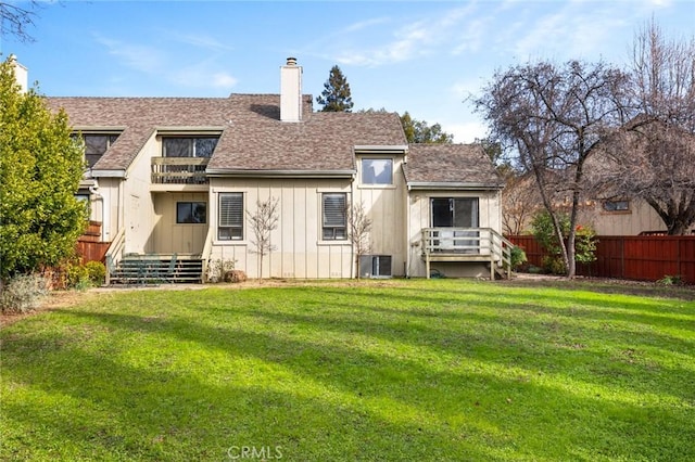 rear view of property featuring central AC, a yard, a chimney, and fence