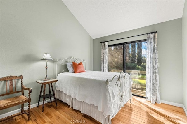 bedroom featuring lofted ceiling, baseboards, and wood finished floors