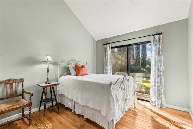 bedroom with baseboards, wood finished floors, multiple windows, and lofted ceiling