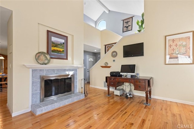 office area with light wood-type flooring, beam ceiling, a fireplace, and baseboards