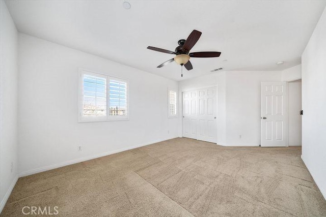 unfurnished bedroom featuring a ceiling fan, a closet, visible vents, and light carpet