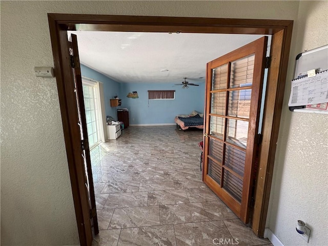 7687 Chase Ave, Hesperia, CA 92345 - hallway with stone finish floor, a textured wall, and baseboards