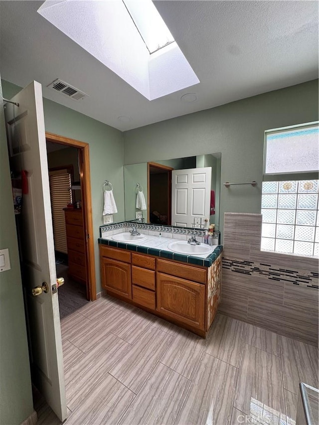 7687 Chase Ave, Hesperia, CA 92345 - bathroom featuring double vanity, a sink, visible vents, and a skylight