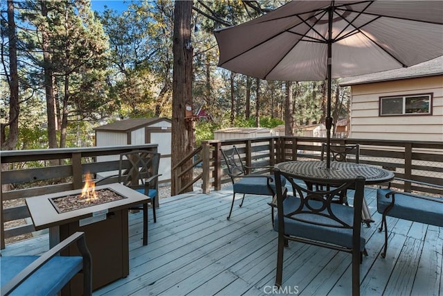 deck with a storage shed, a fire pit, and an outdoor structure