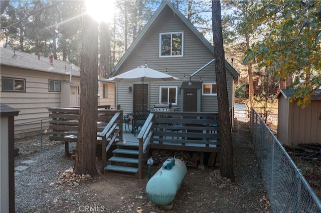 rear view of property with a fenced backyard, a deck, and an outdoor structure