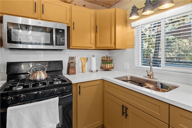 kitchen featuring light brown cabinets, a sink, light countertops, stainless steel microwave, and gas stove