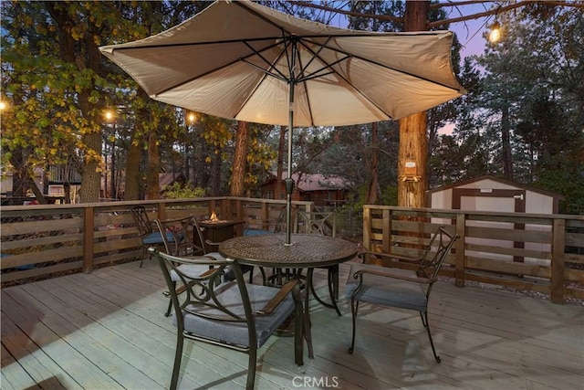 deck at dusk featuring a shed and an outdoor structure