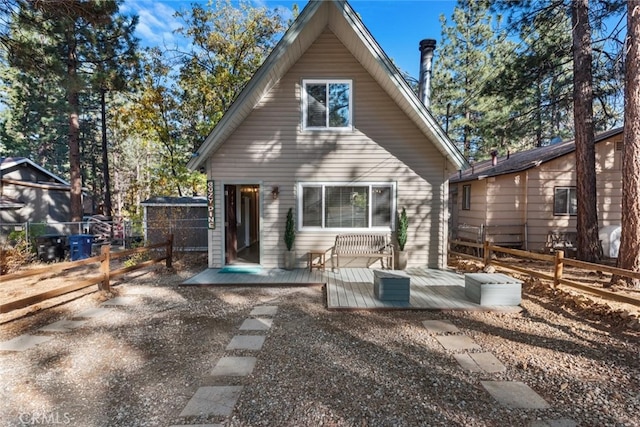 rear view of house with fence and a wooden deck