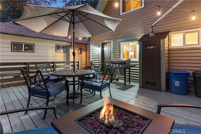 wooden terrace featuring outdoor dining area, a fire pit, and area for grilling