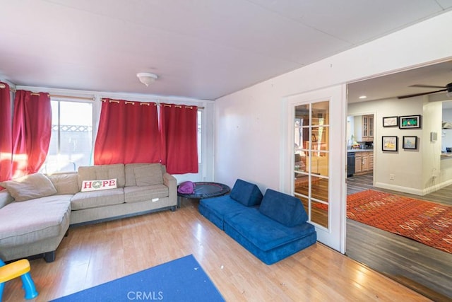 living area featuring ceiling fan, baseboards, and wood finished floors