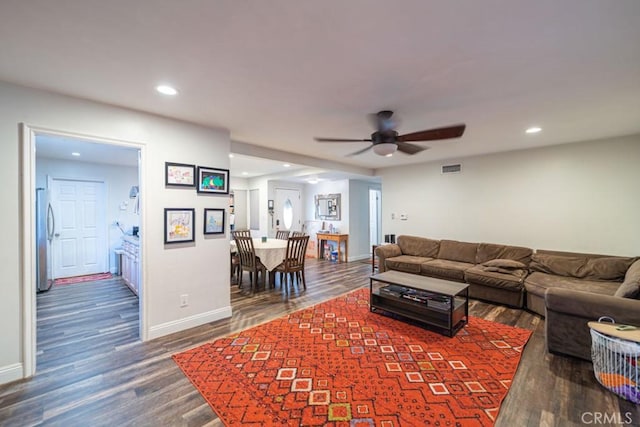 living room featuring recessed lighting, dark wood-style flooring, visible vents, and baseboards