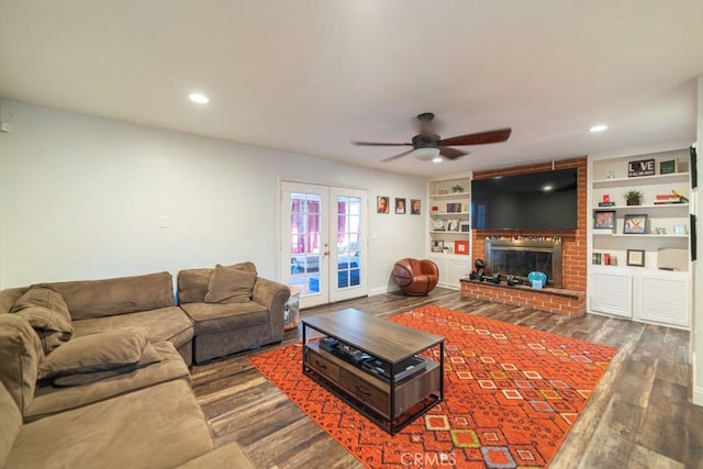 living room with french doors, dark wood-style flooring, a brick fireplace, and recessed lighting