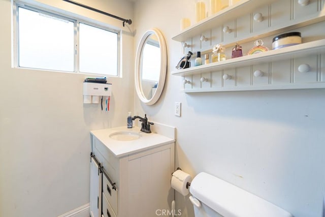 half bathroom with toilet, baseboards, and vanity