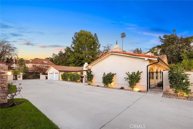 view of front facade featuring a garage, a gate, concrete driveway, and stucco siding