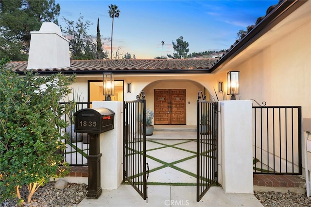 gate at dusk featuring a fenced front yard