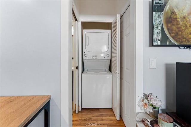 clothes washing area with laundry area, light wood-style floors, and stacked washer / drying machine