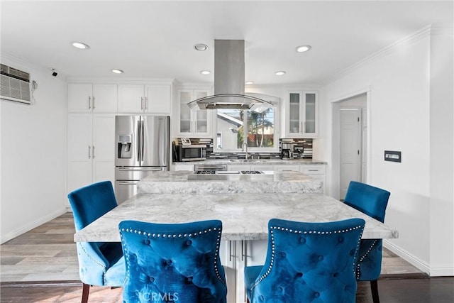 kitchen with glass insert cabinets, white cabinetry, appliances with stainless steel finishes, and a breakfast bar area