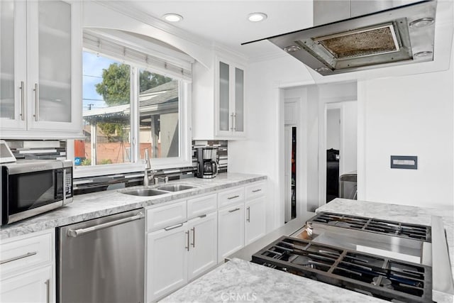 kitchen featuring glass insert cabinets, range hood, stainless steel appliances, white cabinetry, and a sink