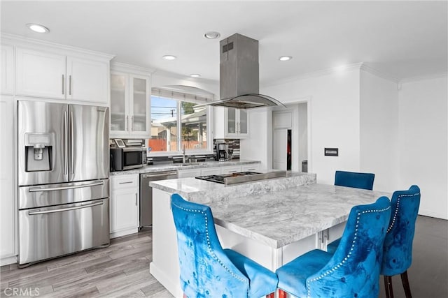 kitchen featuring stainless steel appliances, a breakfast bar area, island exhaust hood, and glass insert cabinets