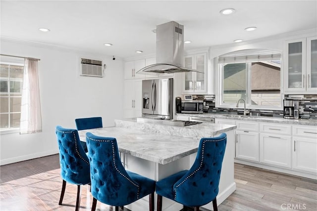 kitchen with appliances with stainless steel finishes, a kitchen bar, and island range hood