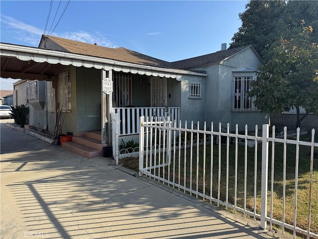 view of front of home with a fenced front yard, a porch, and stucco siding