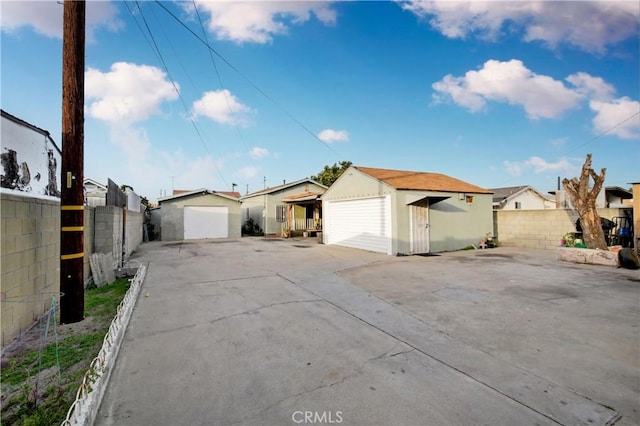 exterior space featuring a residential view, a fenced backyard, a detached garage, and an outdoor structure